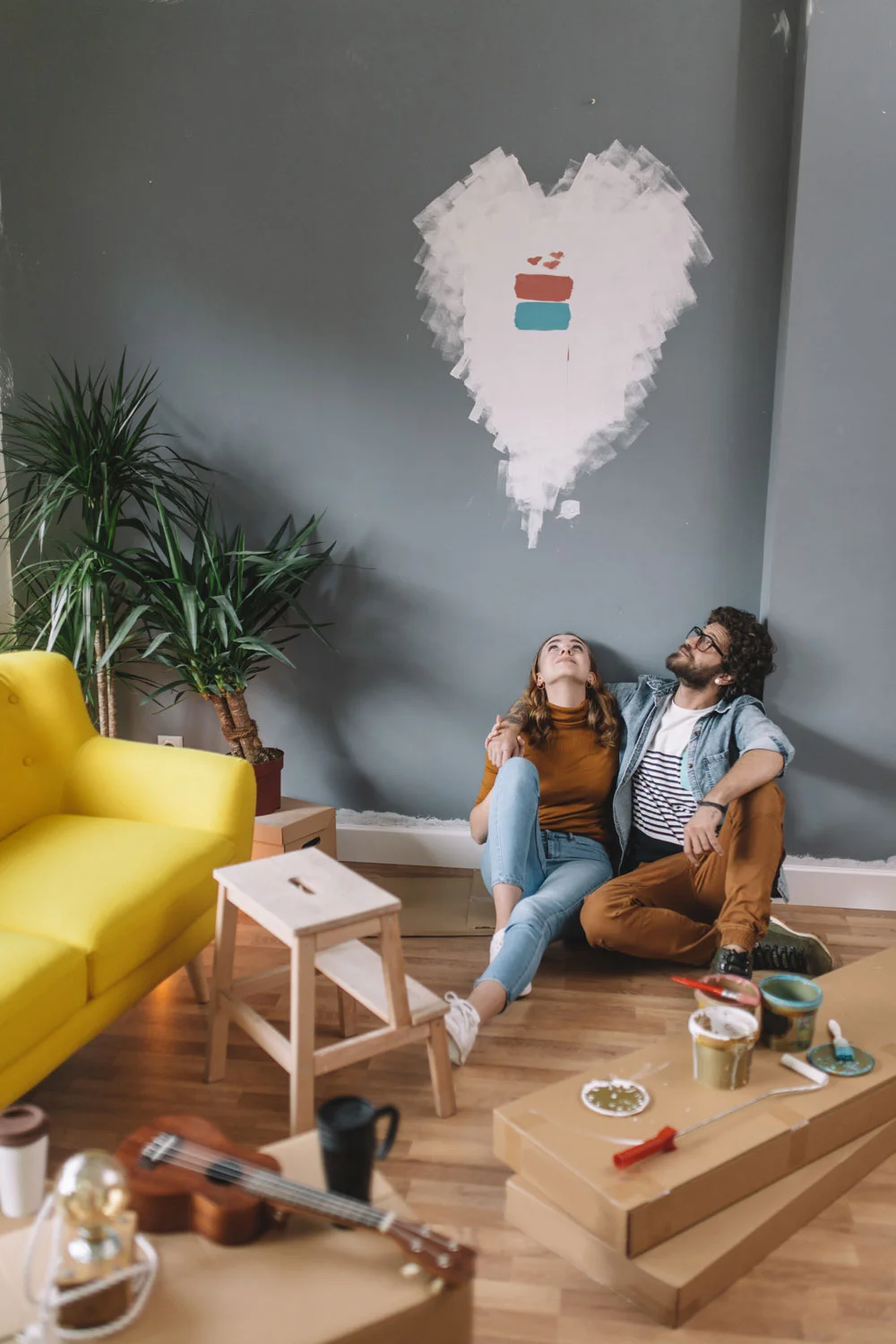 Pareja sentado en el piso, pensando. Pintando casa