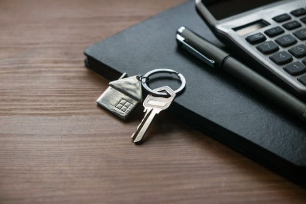 llavero con una casa de metal sobre una libreta que es y por que conviene la plusvalia inmobiliaria